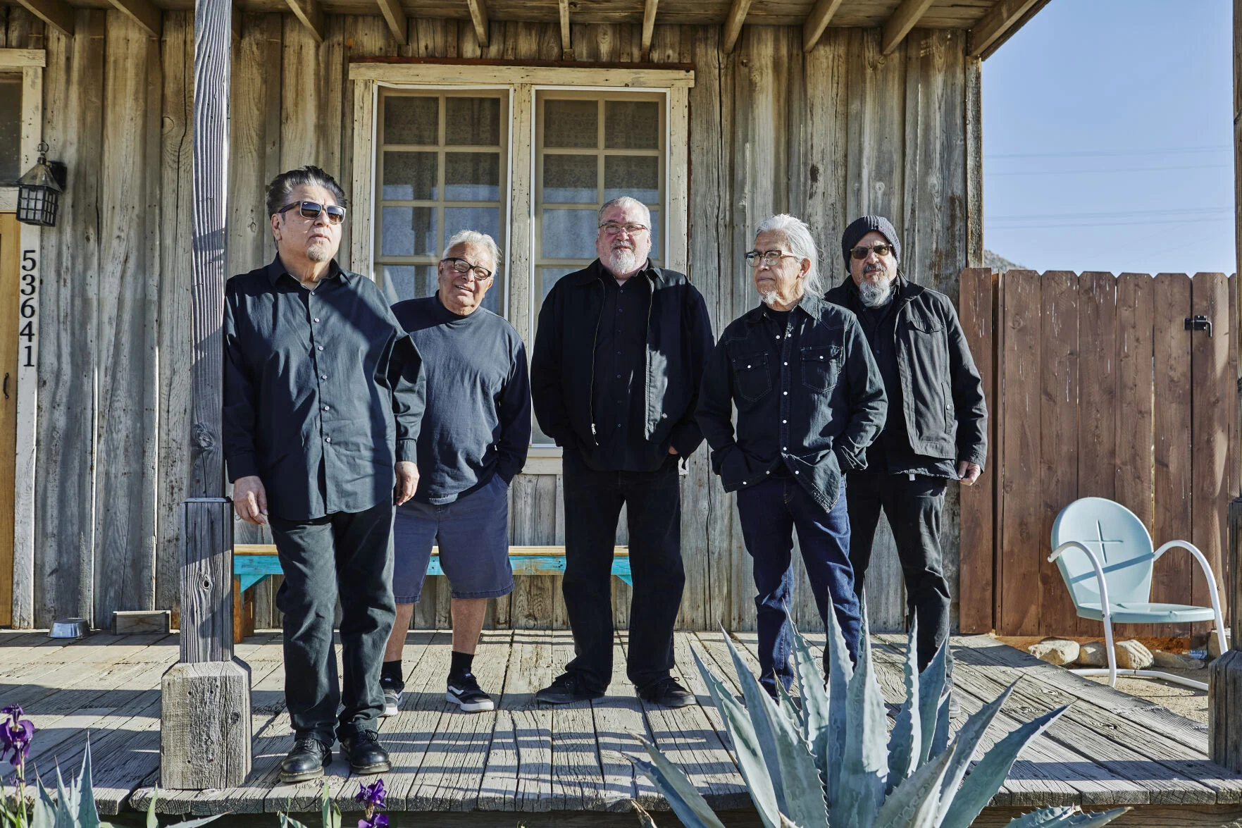 The members of the rock band Los Lobos - 5 men posing outside a house