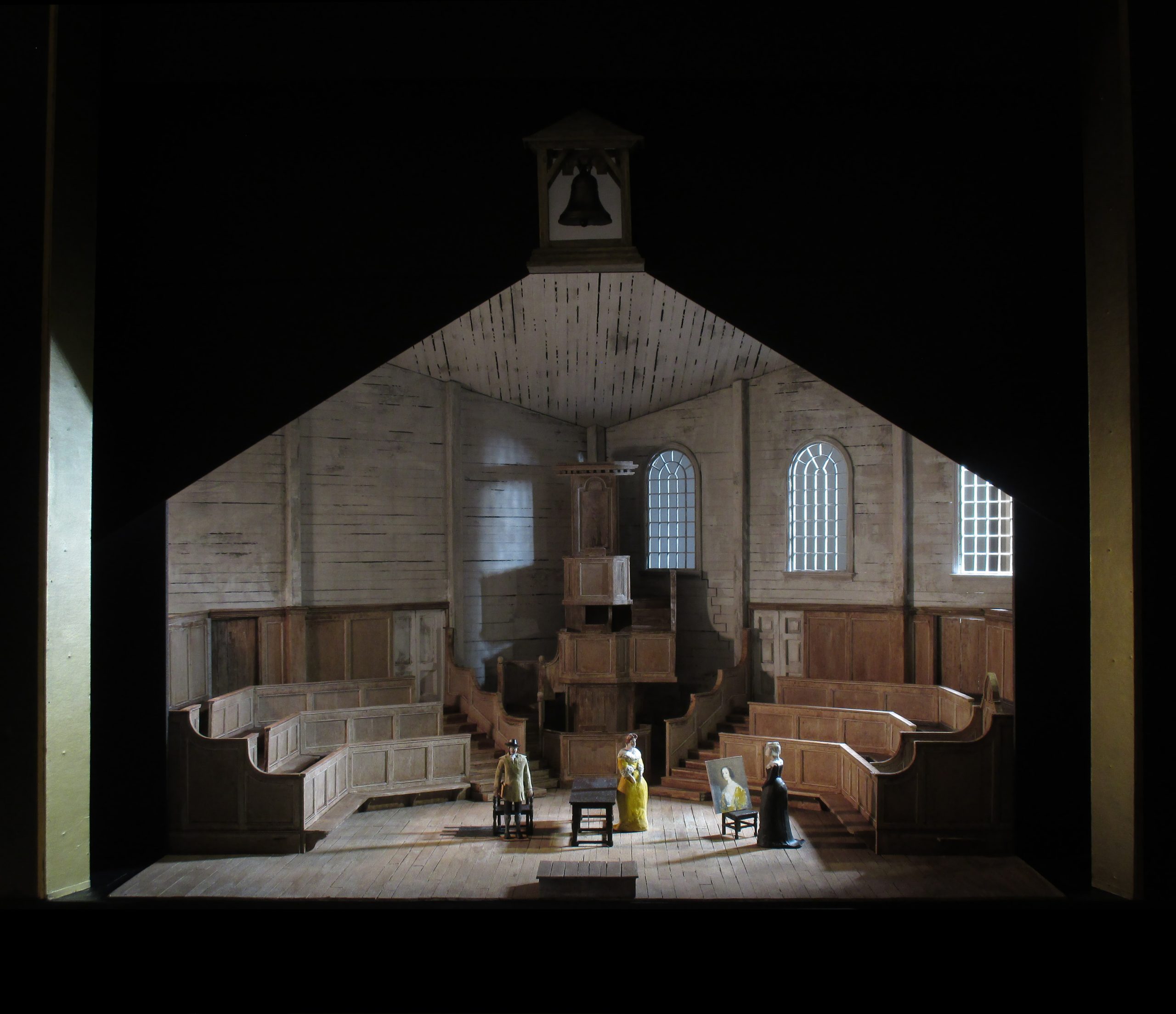 An opera stage set forming a church interior, with three figures standing within