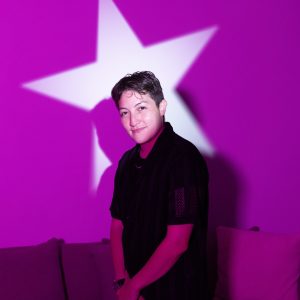 A portrait of DJ RVMBA in front of a purple background