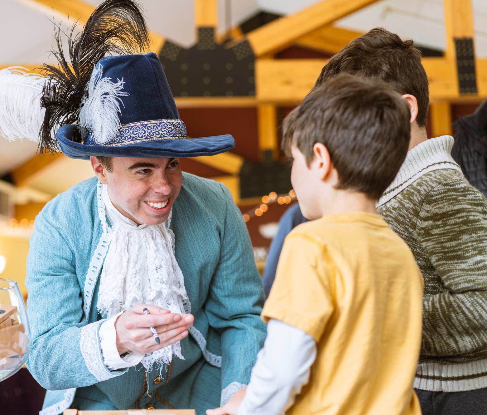A man in an elegant hat and old fashioned opera outfit, speaking with students