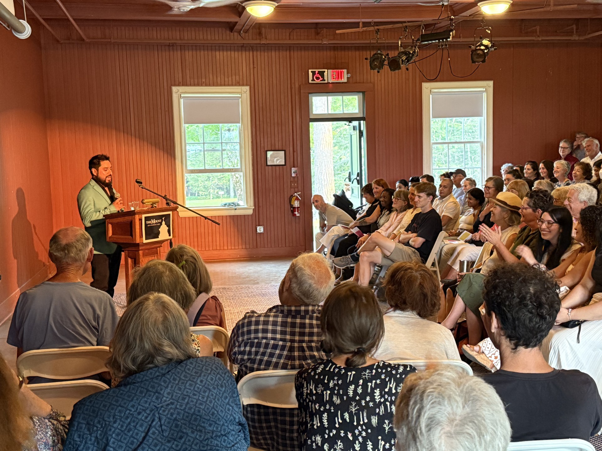 A speaker at a podium, addressing a seated audience
