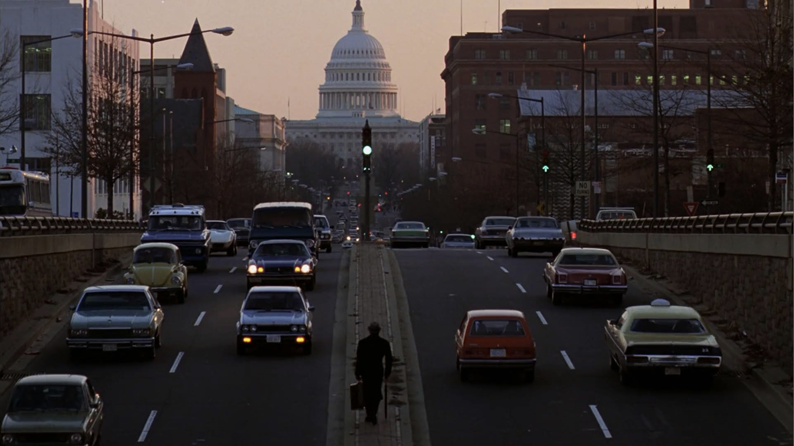 Still frame from the film Being There, featuring a man walking in a highway divider in Washington D.C.