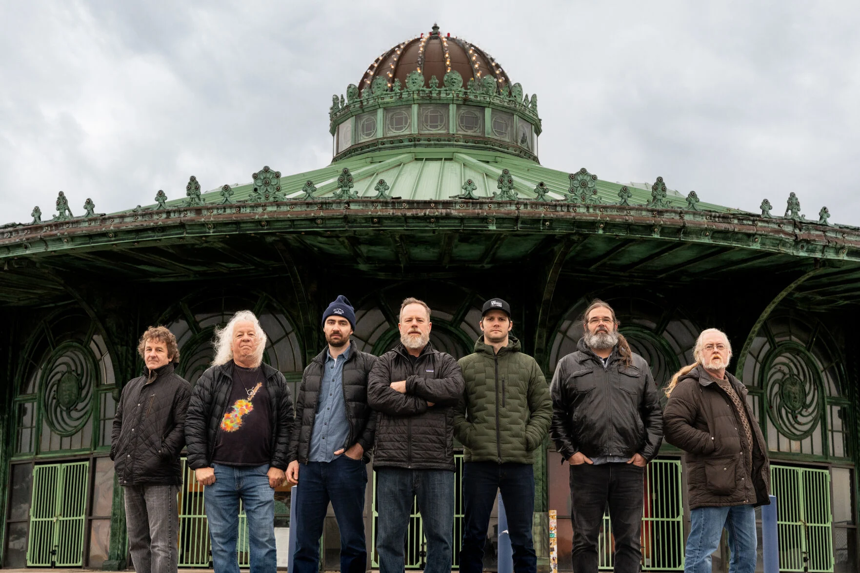 The seven members of the band Railroad Earth standing before a historic structure