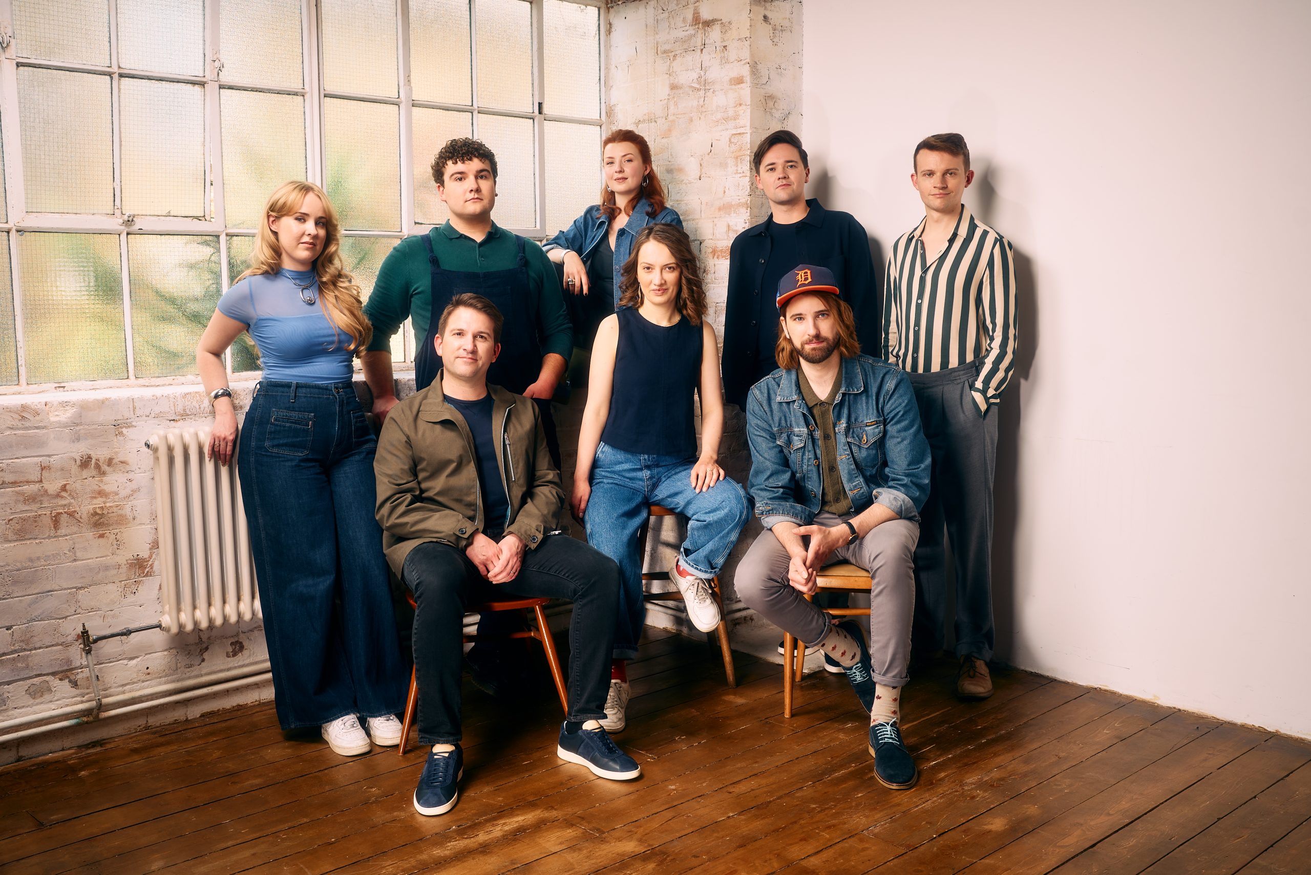 Eight singers posed together in a studio