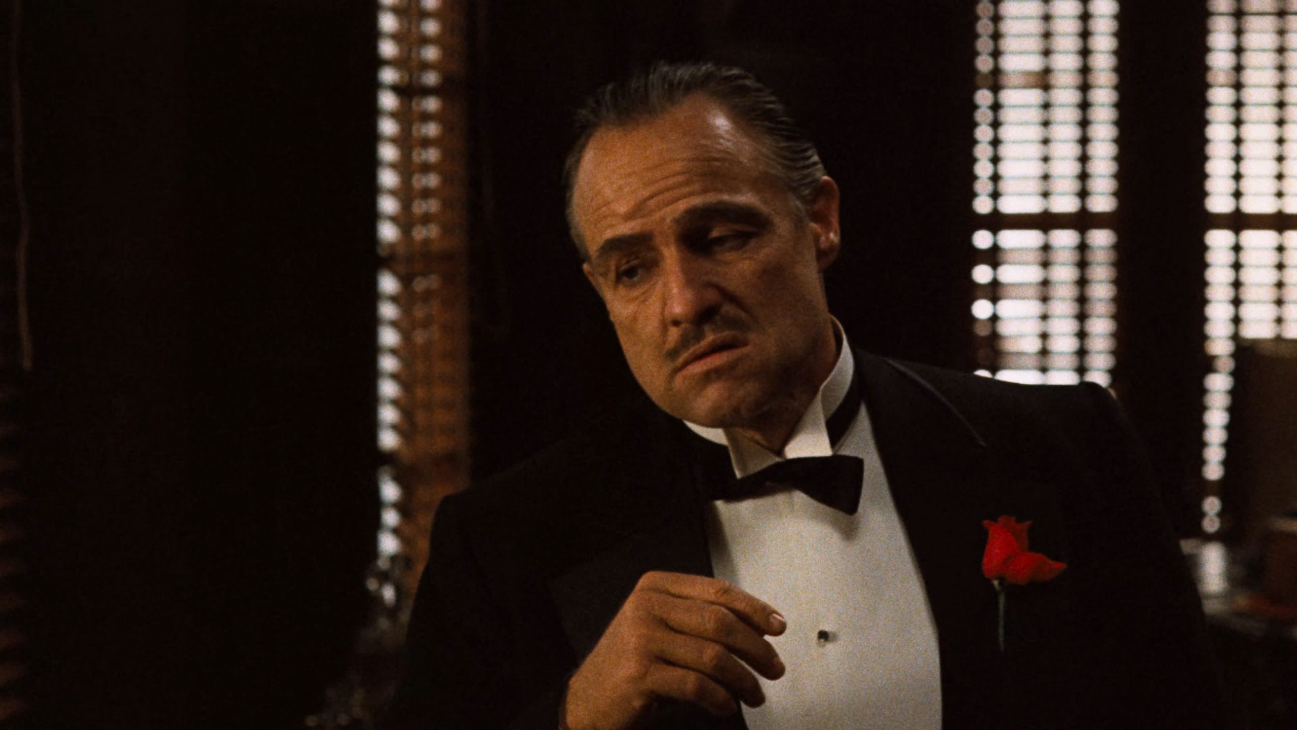 Don Vito Corleone (Marlon Brando) sitting at a desk in a dimly lit room