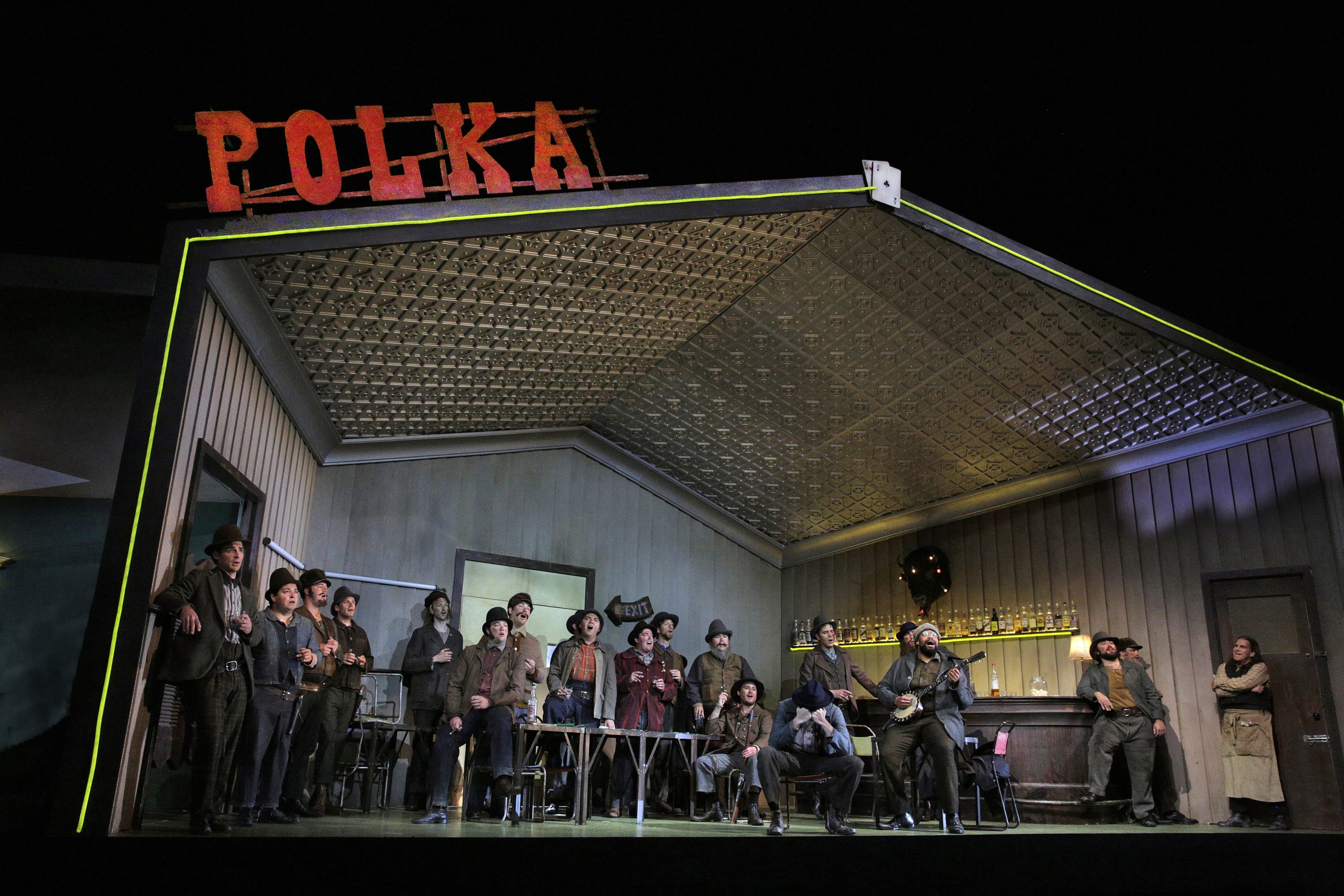 An opera stage set with a large group of men in a barroom