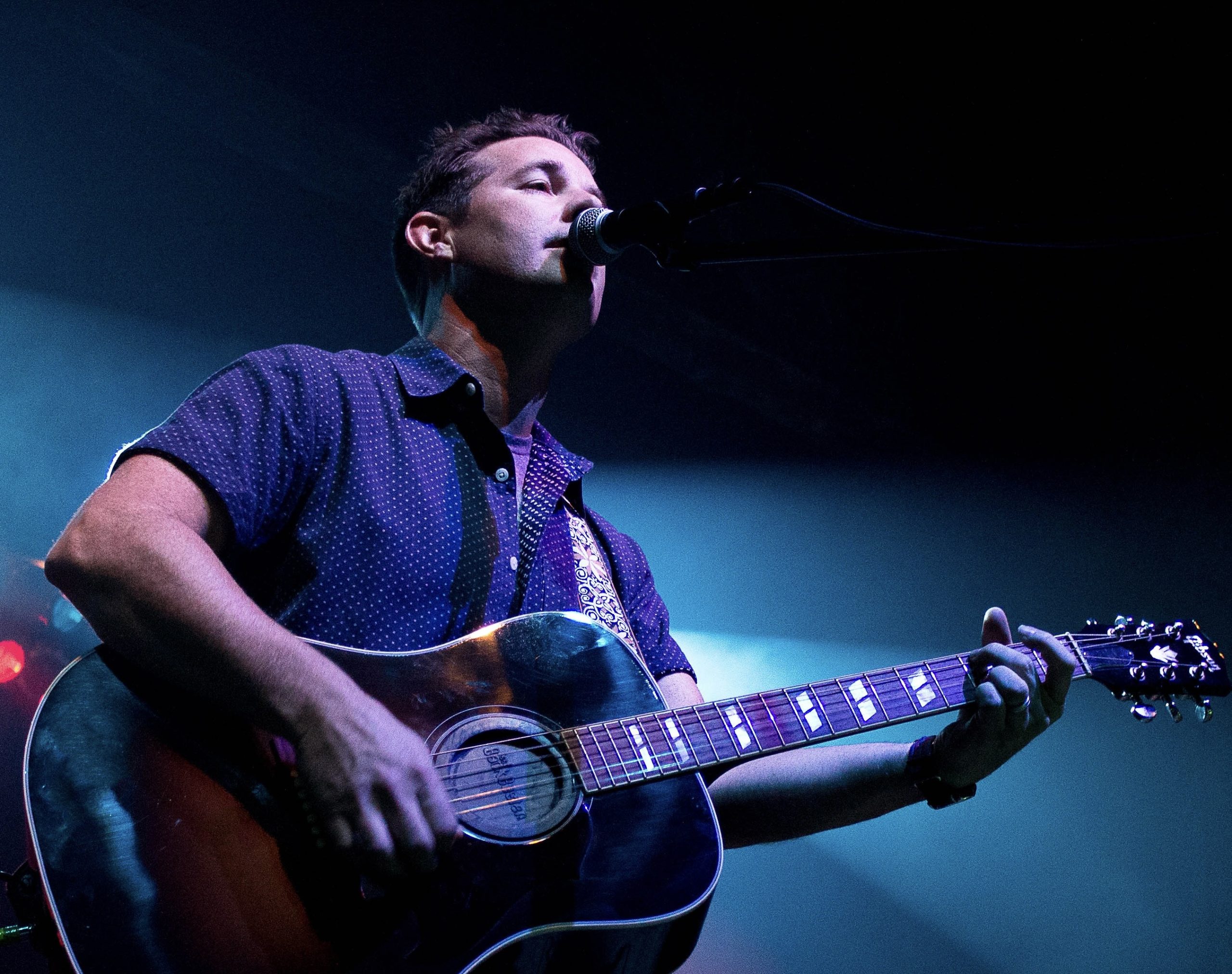 A man playing a guitar in a darkened indoor venue